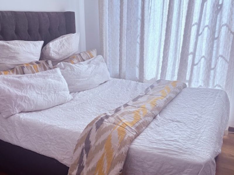 A bedroom featuring laminate flooring and a window with curtains.