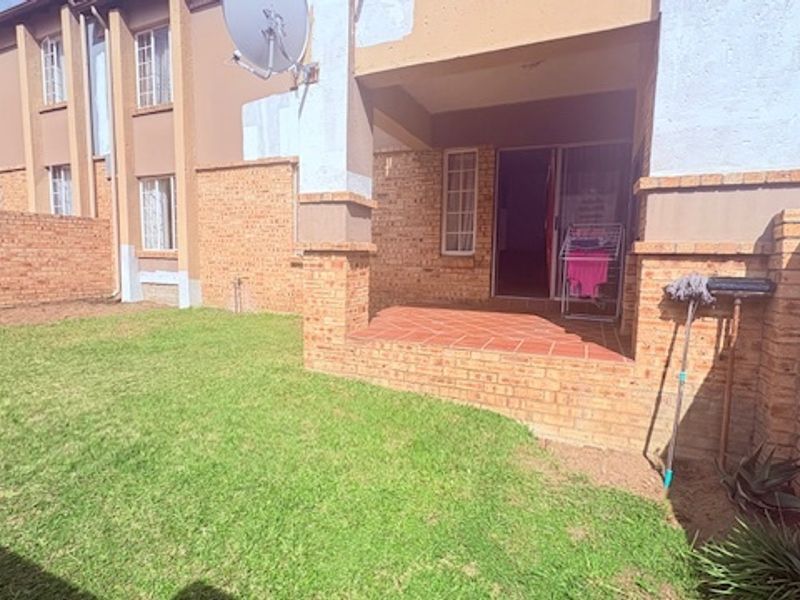 A private rear garden featuring a paved patio area, brick boundary walls, and a small lawn, providing a functional outdoor space for the townhouse.