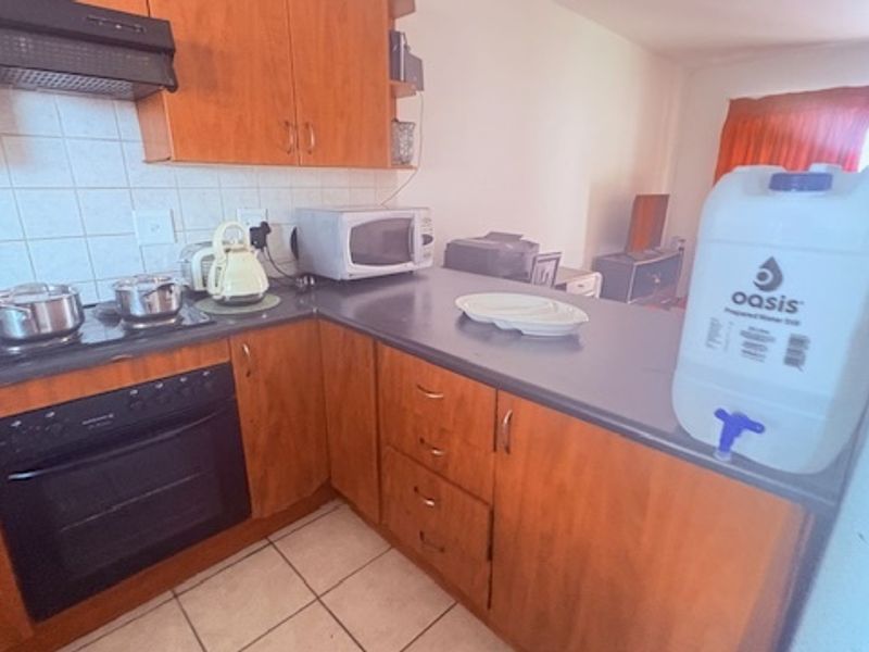 A functional kitchen featuring wood-finish cabinetry, a built-in oven, extractor fan, and tiled backsplash, offering a practical layout for daily meal preparation.