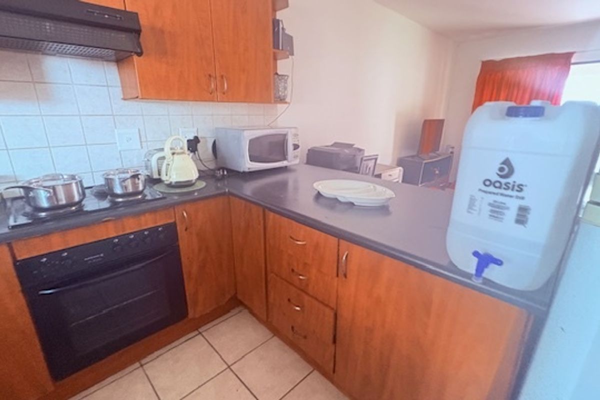 A functional kitchen featuring wood-finish cabinetry, a built-in oven, extractor fan, and tiled backsplash, offering a practical layout for daily meal preparation.