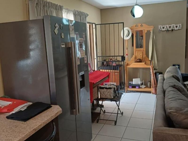 Open plan living area featuring tiled flooring and a security gate leading to the exterior, providing a functional layout for daily living.