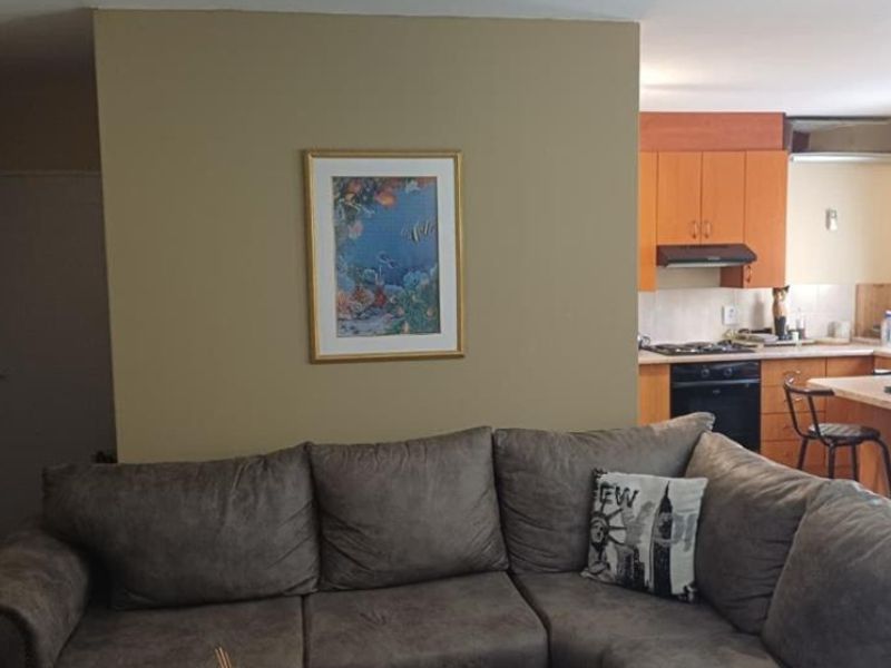 Open plan living area featuring a kitchen with built-in cabinetry, oven, hob, and extractor fan, flowing into the adjacent living space.