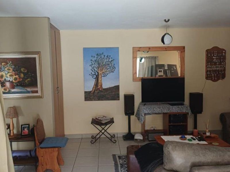 A living room area featuring tiled flooring and a built-in storage cupboard, providing a functional space for relaxation.