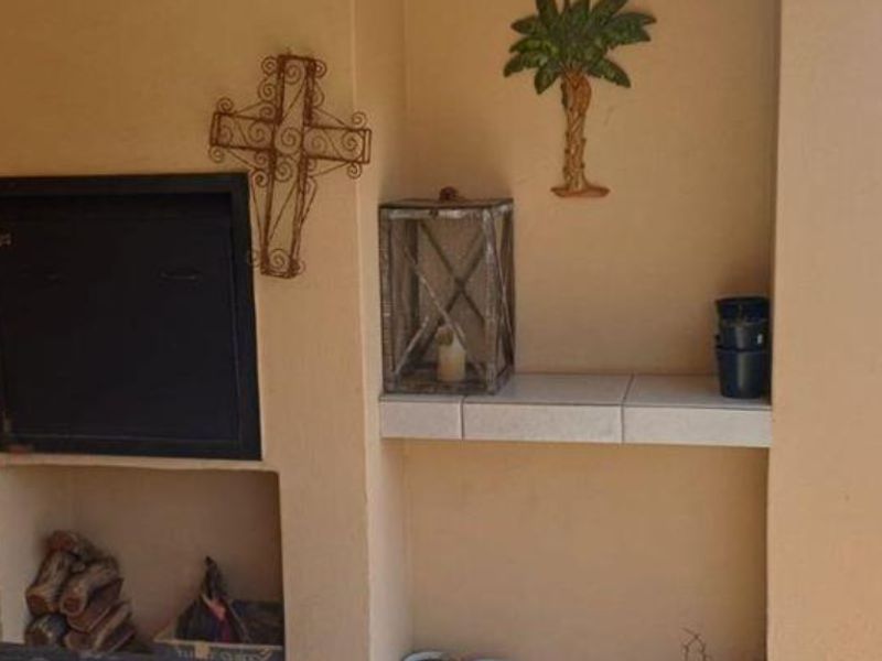 Covered patio area featuring a built-in braai and a tiled prep surface, providing a functional outdoor entertainment space.
