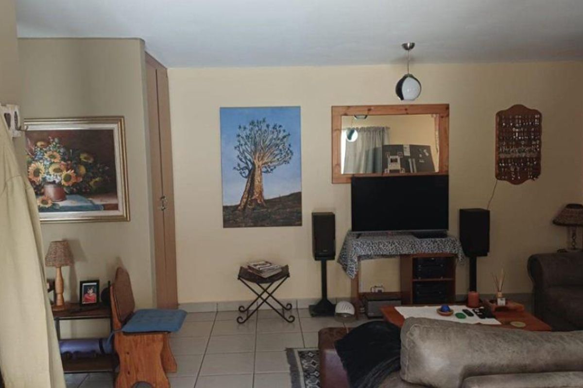 A living room area featuring tiled flooring and a built-in storage cupboard, providing a functional space for relaxation.