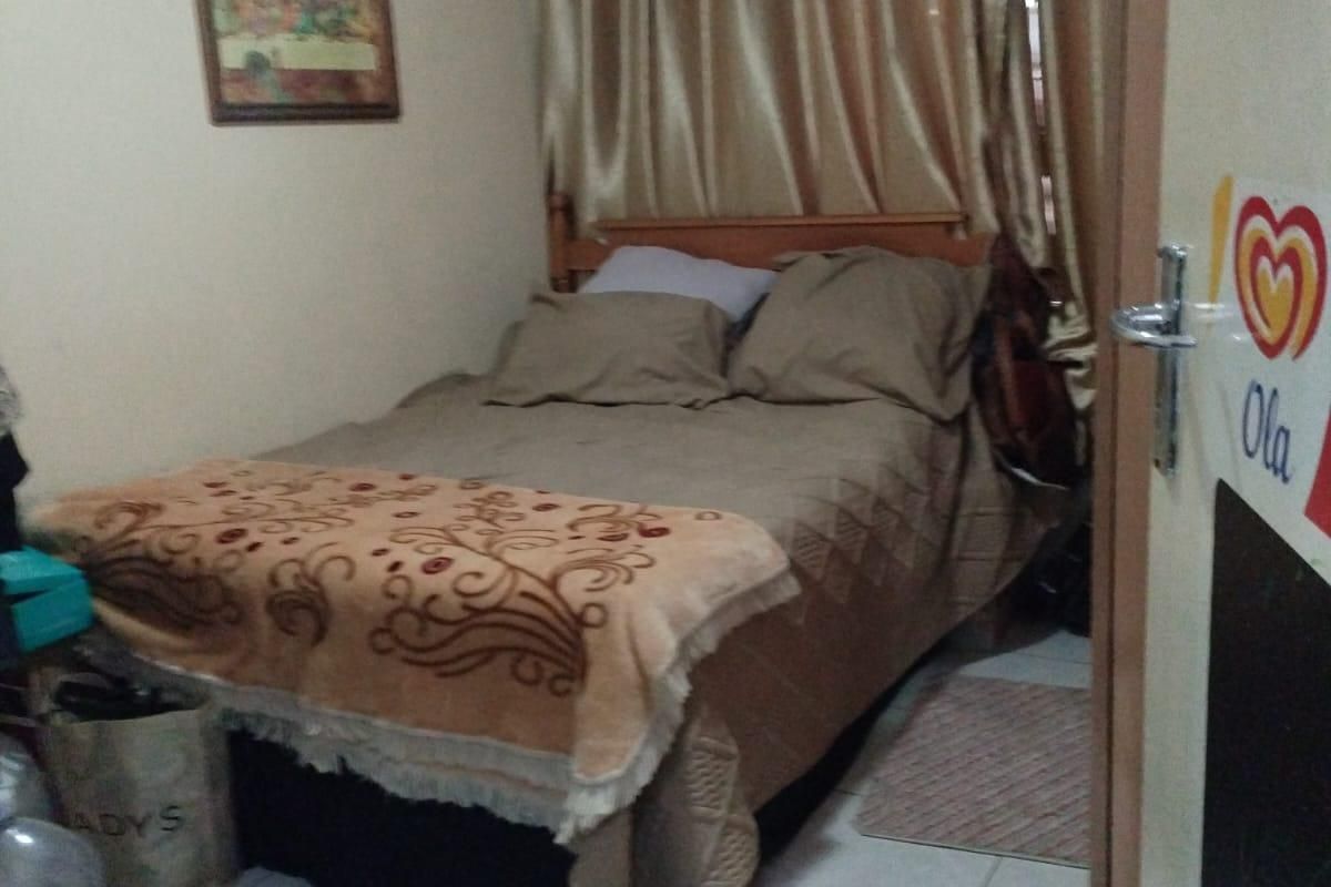 A compact bedroom featuring tiled flooring and neutral wall finishes, providing a functional sleeping space.