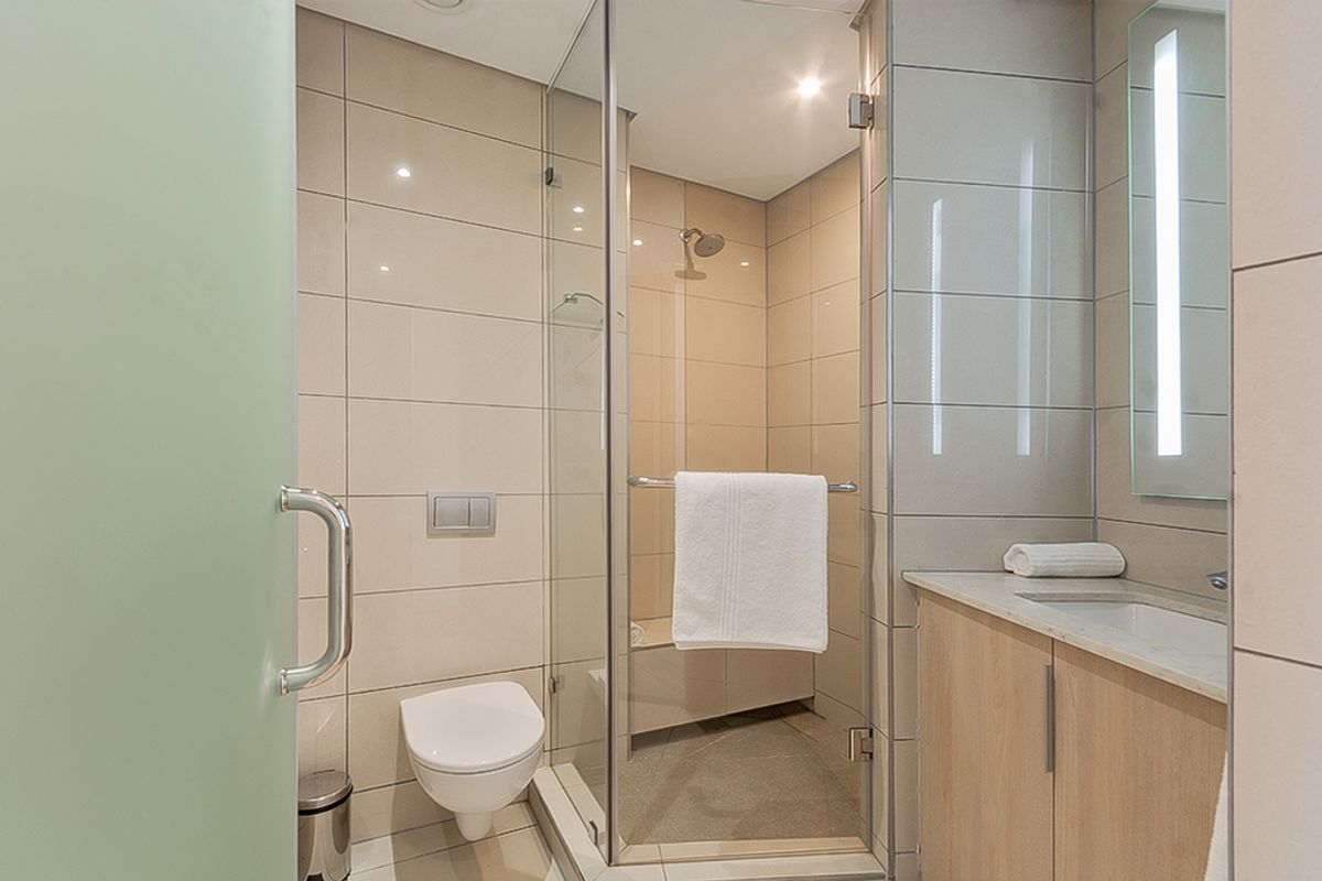 Modern bathroom featuring a glass-enclosed shower, wall-mounted toilet, and a vanity cabinet with an integrated sink and stone countertop.