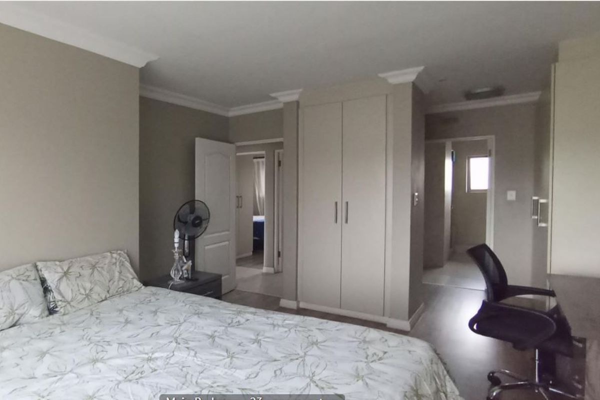 A well-maintained bedroom featuring neutral wall tones, built-in cupboards, decorative cornice, and durable laminate flooring.
