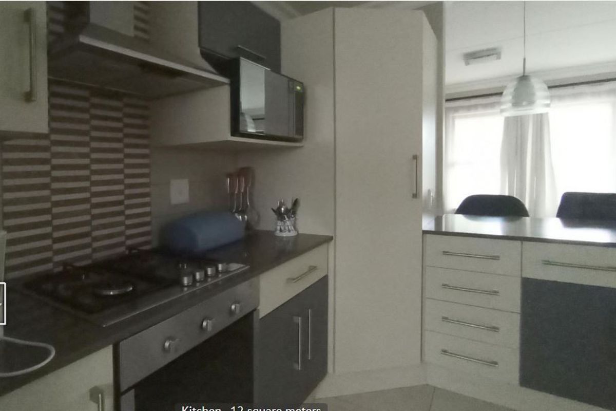 Modern kitchen featuring built-in oven, gas hob, extractor fan, integrated microwave, and ample cabinetry with a tiled backsplash and breakfast counter.