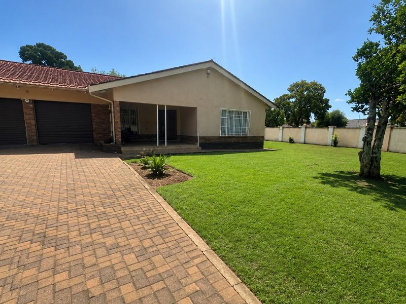 Front view of a residential house featuring a paved driveway, double garage, covered entrance porch, and a well-maintained lawn.
