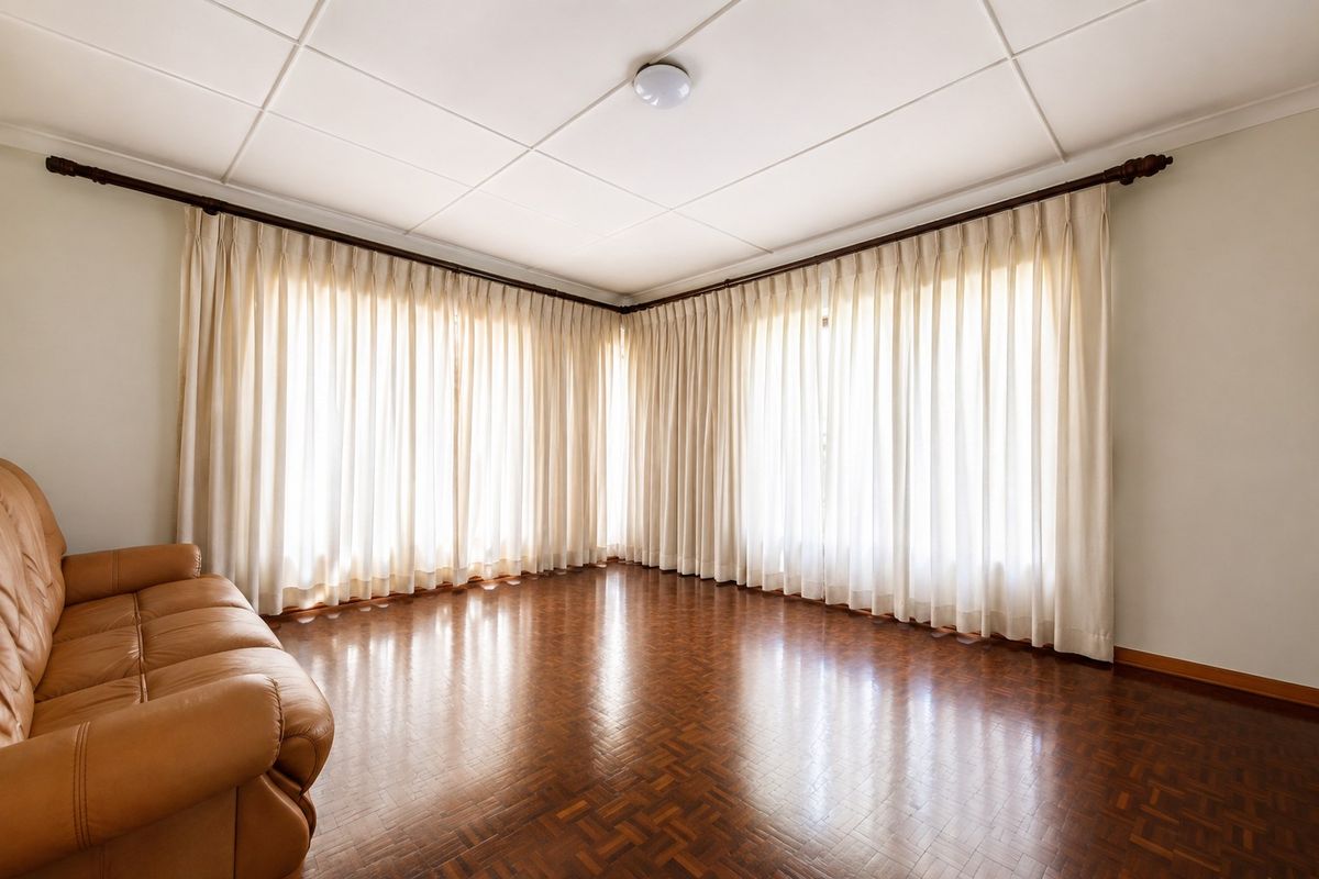 A spacious living room featuring classic parquet flooring, large windows with floor-to-ceiling curtains, and a tiled ceiling.