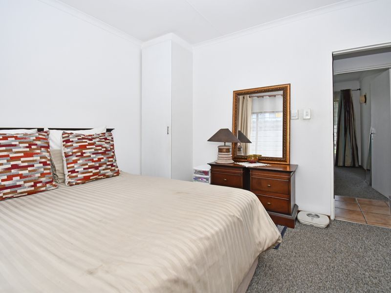 A bedroom featuring neutral wall finishes, carpeted flooring, and a built-in cupboard, providing a functional and well-lit sleeping space.