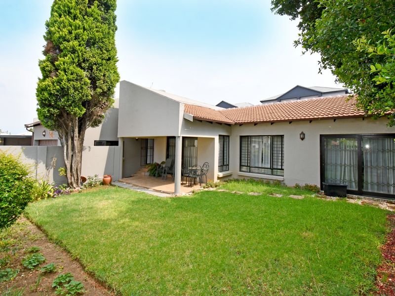 Rear view of the cluster property featuring a covered patio, well-maintained lawn, and sliding glass doors providing access to the interior living spaces.