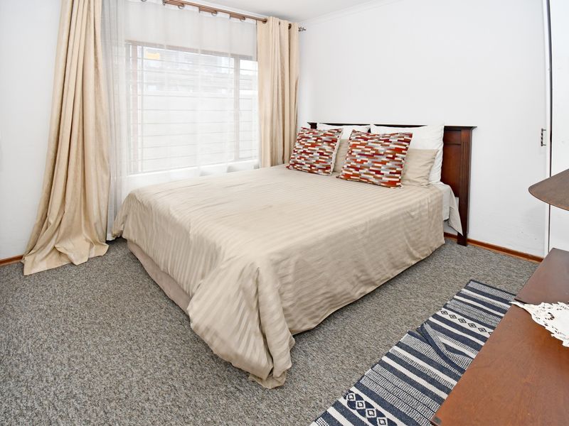 A well-lit bedroom featuring neutral carpeting and a built-in cupboard, offering a comfortable and functional living space.
