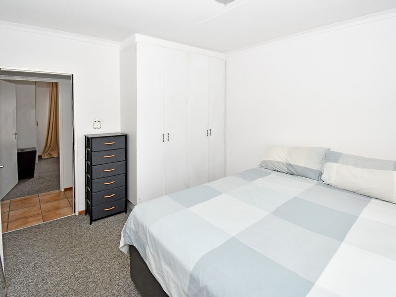 A functional bedroom featuring built-in cupboards and neutral carpeting, providing a clean and simple living space.