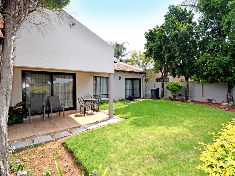 Rear view of the property featuring a covered tiled patio, sliding door access, and a private garden with a perimeter wall.