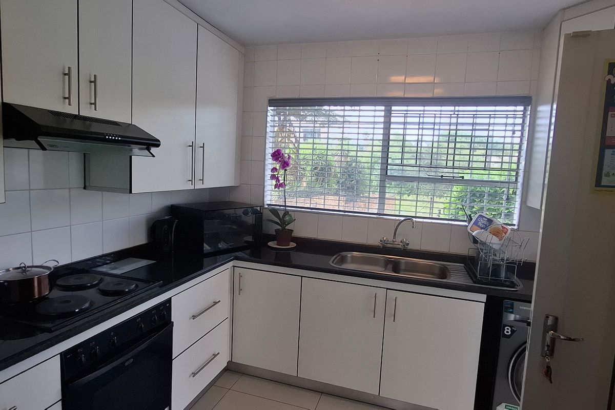 Functional kitchen featuring white cabinetry, black granite countertops, integrated electric oven and hob, and a double bowl sink with tiled splashback.