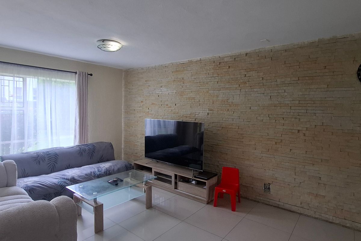 A comfortable living room featuring a textured stone cladding feature wall and neutral tiled flooring, providing a solid foundation for modern interior updates.
