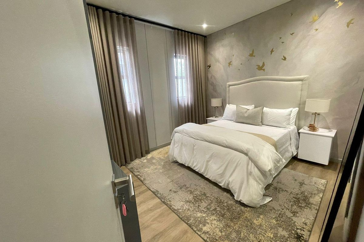 A well-maintained bedroom featuring laminate flooring, recessed lighting, and a decorative feature wall with floor-to-ceiling curtains.