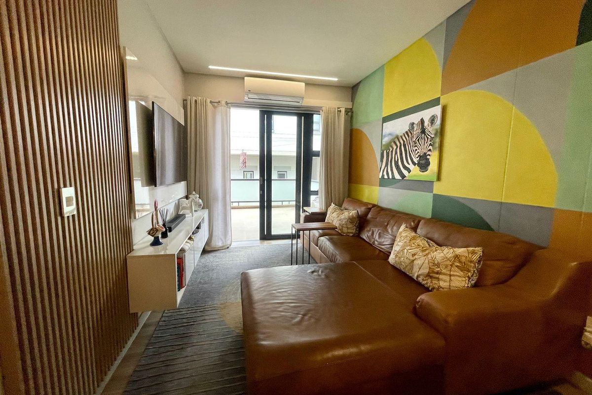 Modern living room featuring timber slat wall paneling, recessed lighting, and direct access to a private balcony through sliding glass doors.