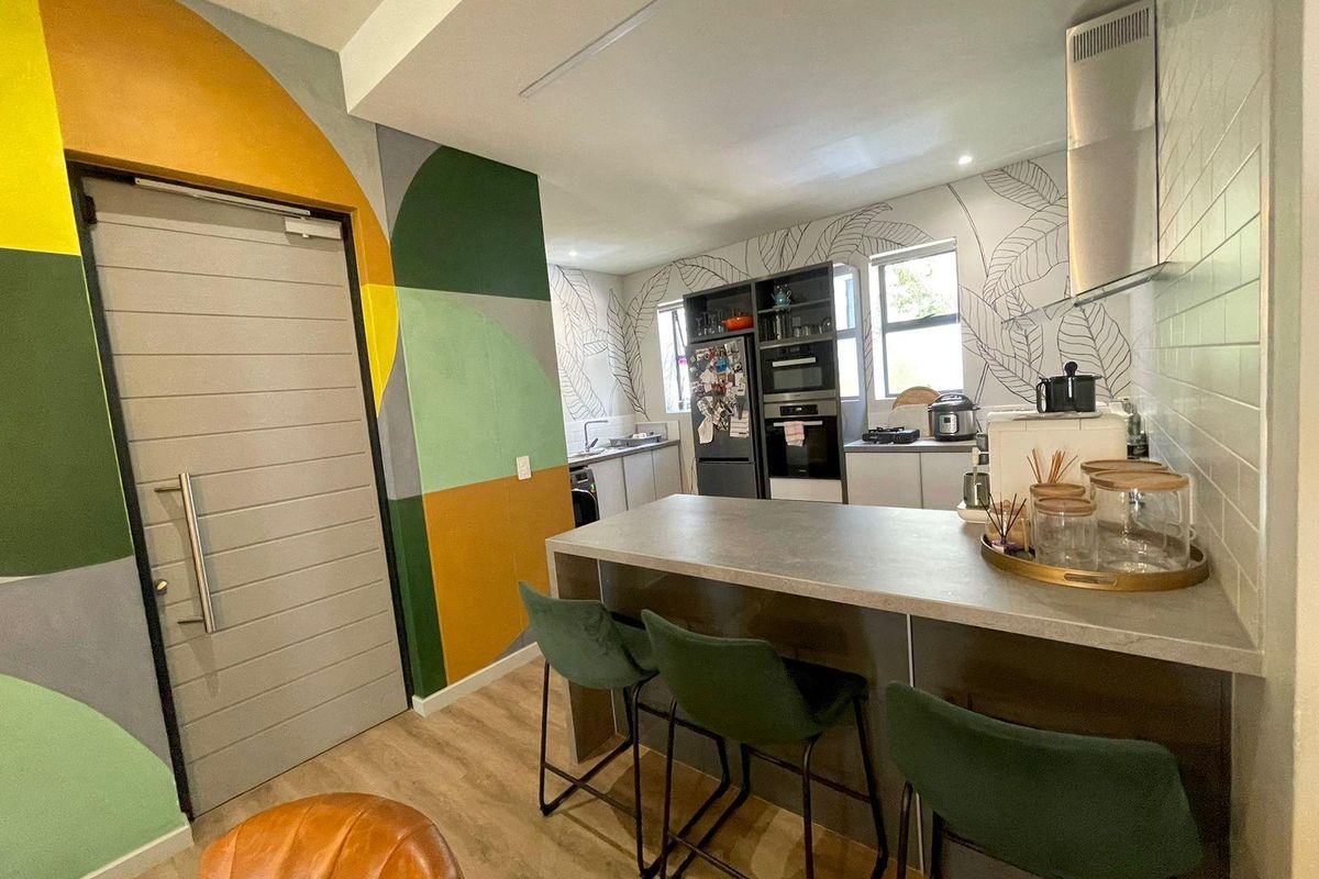 Modern kitchen featuring a central island, built-in oven, extractor fan, and custom wall mural, offering a functional and stylish cooking and dining space.