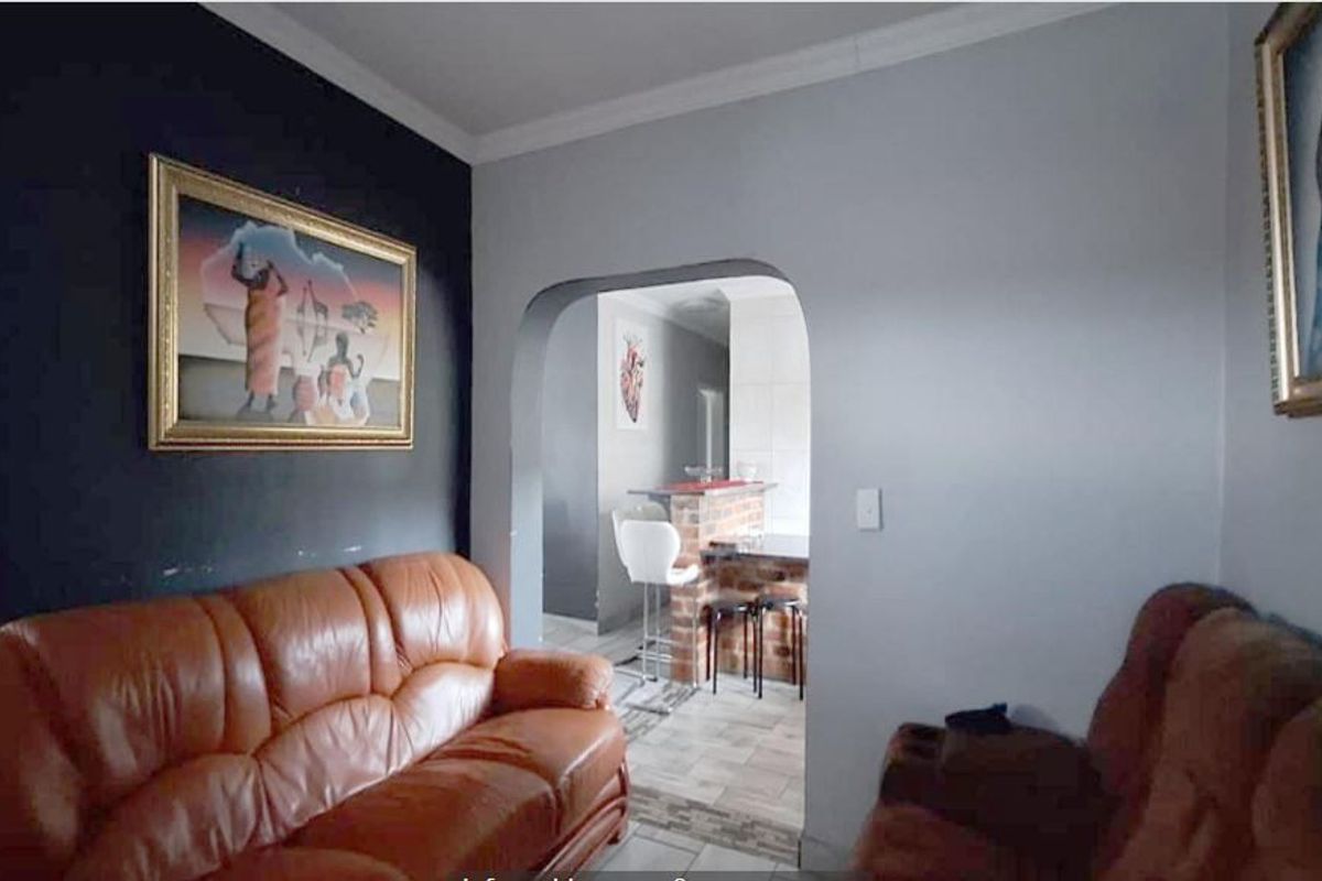 A living room featuring an arched entryway leading to a kitchen area with a breakfast bar and tiled flooring.