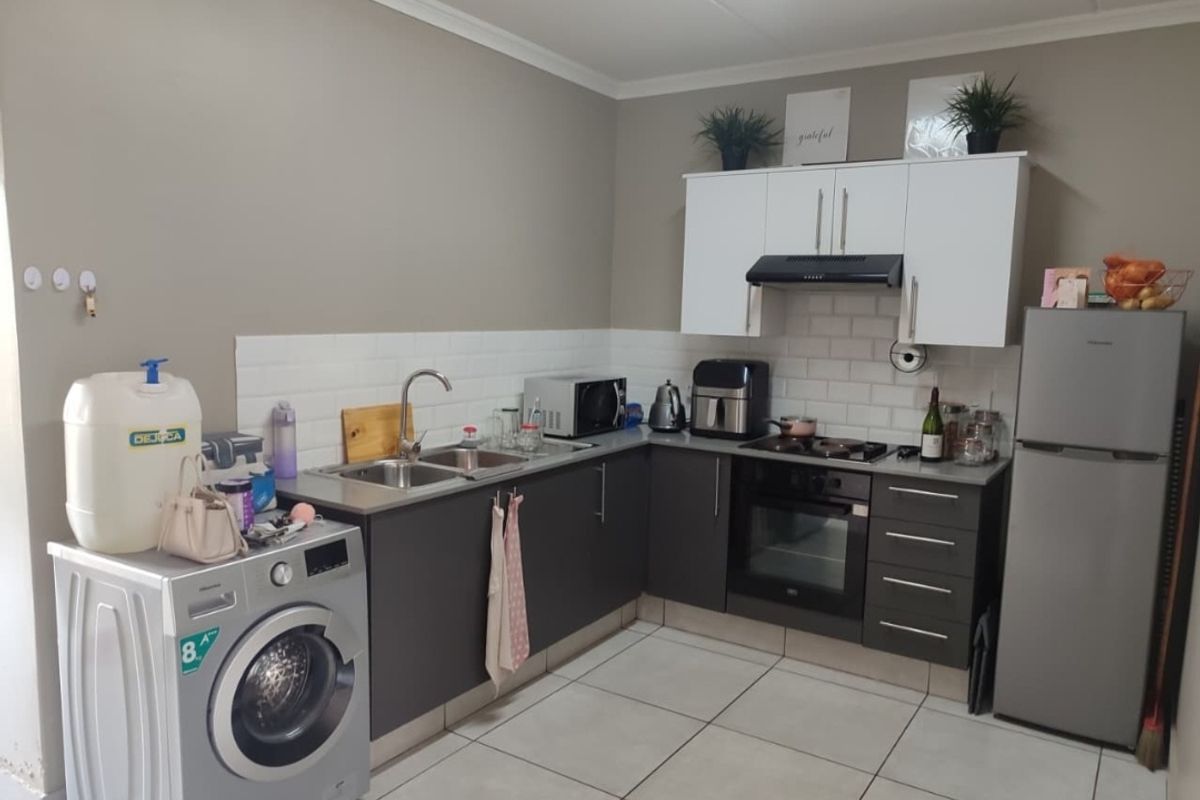 A functional kitchen featuring dark lower cabinetry, white upper cabinets, subway tile backsplash, built-in oven, hob, extractor fan, and tiled flooring.