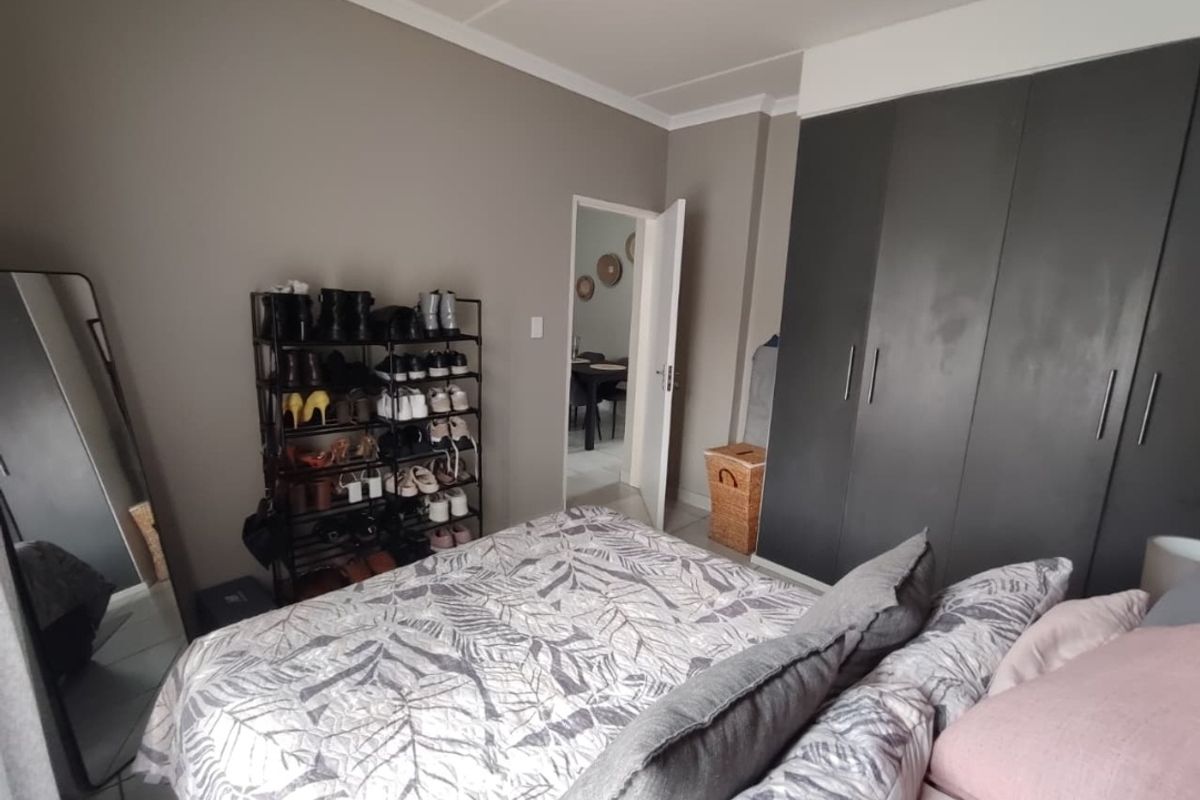 A bedroom featuring neutral wall tones and dark grey built-in cupboards, providing ample storage space.