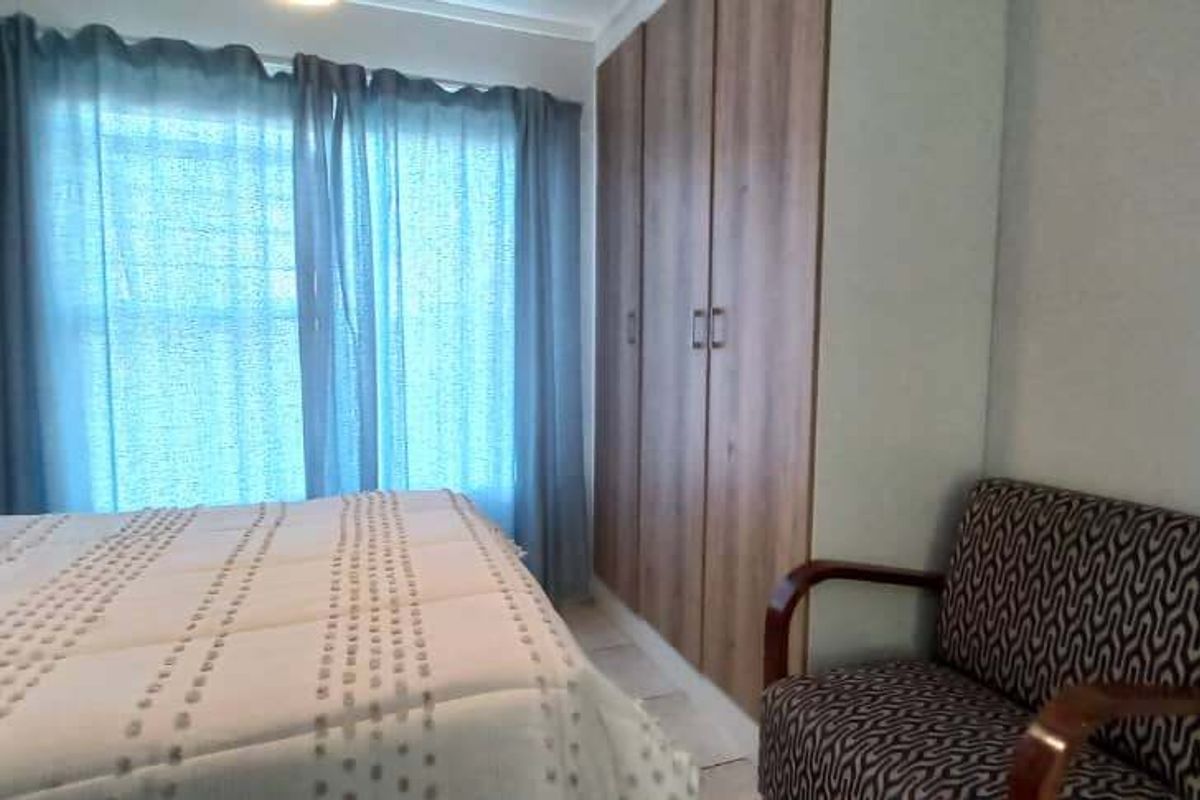 A well-maintained bedroom featuring a large built-in wardrobe with wood-finish doors and a sliding door providing natural light.