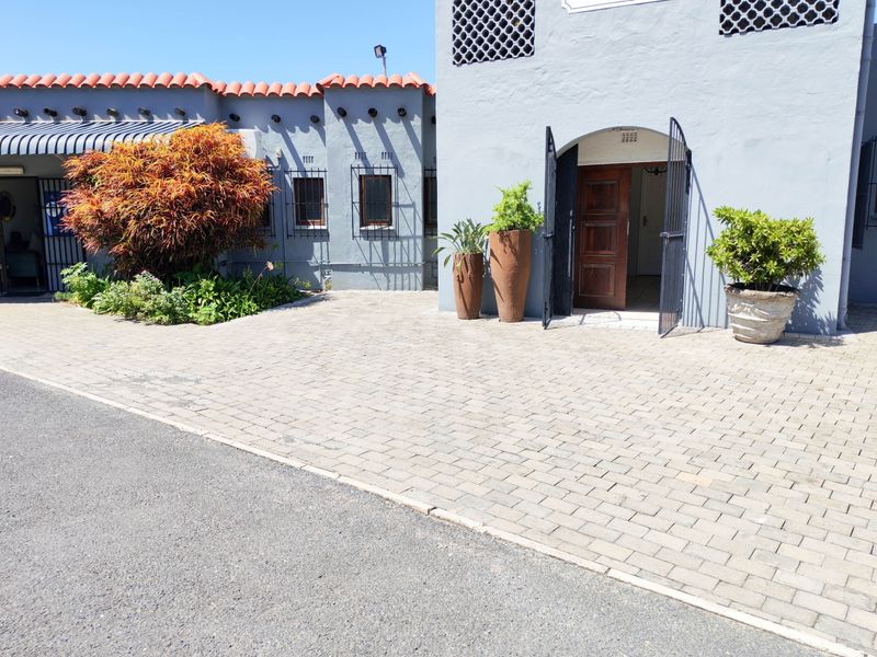 Front exterior view of a commercial property featuring a paved driveway, terracotta roof tiles, and a secure timber entrance door.