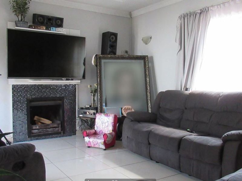 A living room featuring a fireplace with a mosaic tile surround and light-colored tiled flooring.