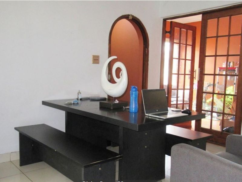 A living area featuring tiled flooring, an arched doorway, and wooden-framed french doors leading to an adjacent space.