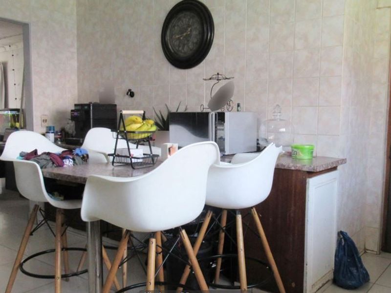 A functional kitchen area featuring tiled wall splashbacks, laminate countertops, and built-in cabinetry, offering potential for a modern renovation.