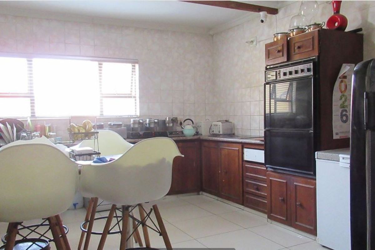 A dated kitchen featuring traditional wood-finish cabinetry, tiled walls, and a built-in oven, offering potential for a modern renovation.