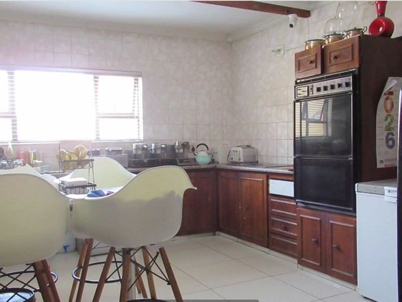 A dated kitchen featuring traditional wood-finish cabinetry, tiled walls, and a built-in oven, offering potential for a modern renovation.