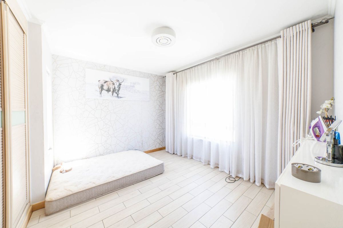 A bright bedroom featuring tiled flooring, a built-in wardrobe, and floor-to-ceiling curtains, offering a clean and neutral space ready for personalization.