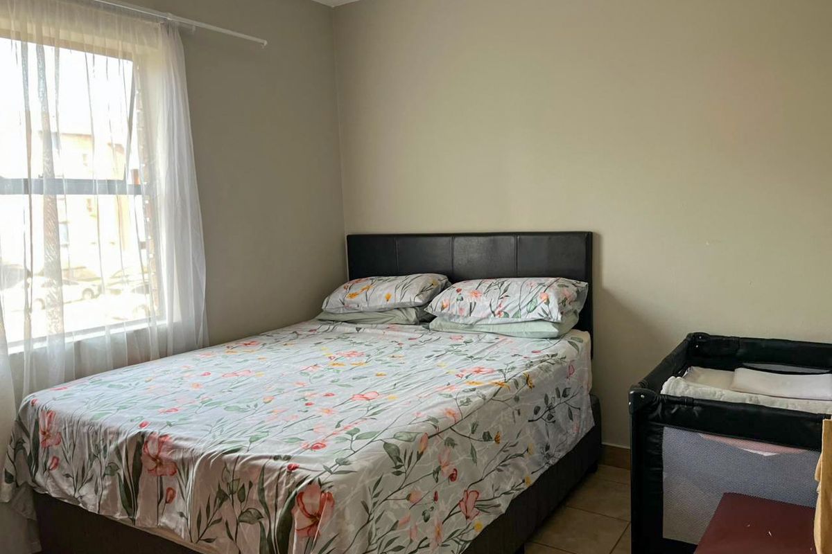 A functional bedroom featuring tiled flooring and natural light from a side window.