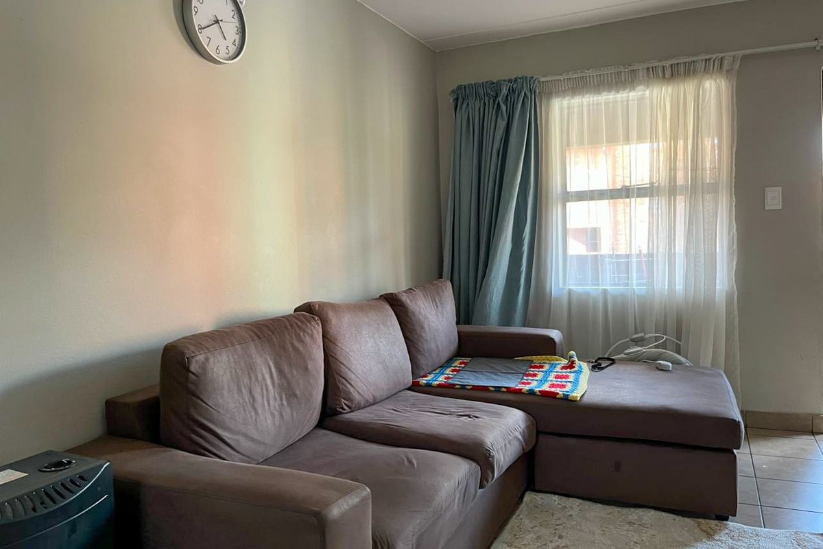 A living room area featuring tiled flooring and window treatments, providing a functional space for relaxation.