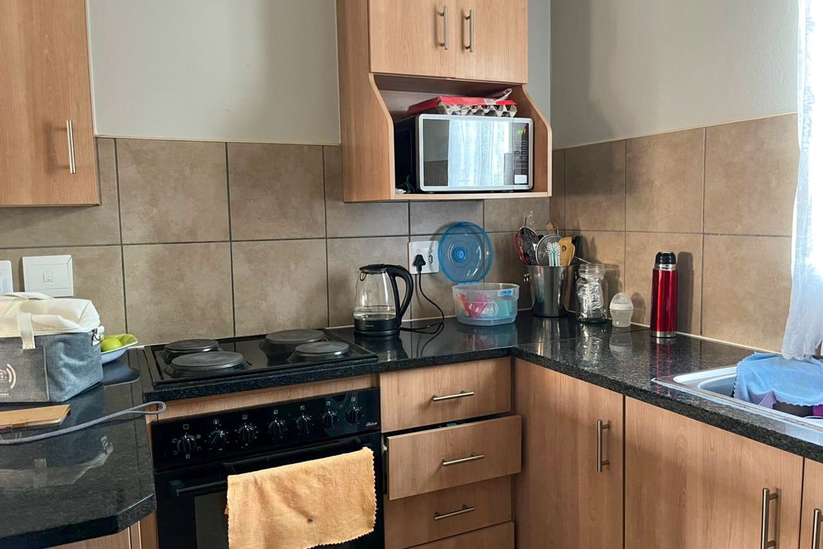 A functional kitchen featuring laminate cabinetry, granite countertops, a tiled backsplash, and a built-in electric oven and hob.
