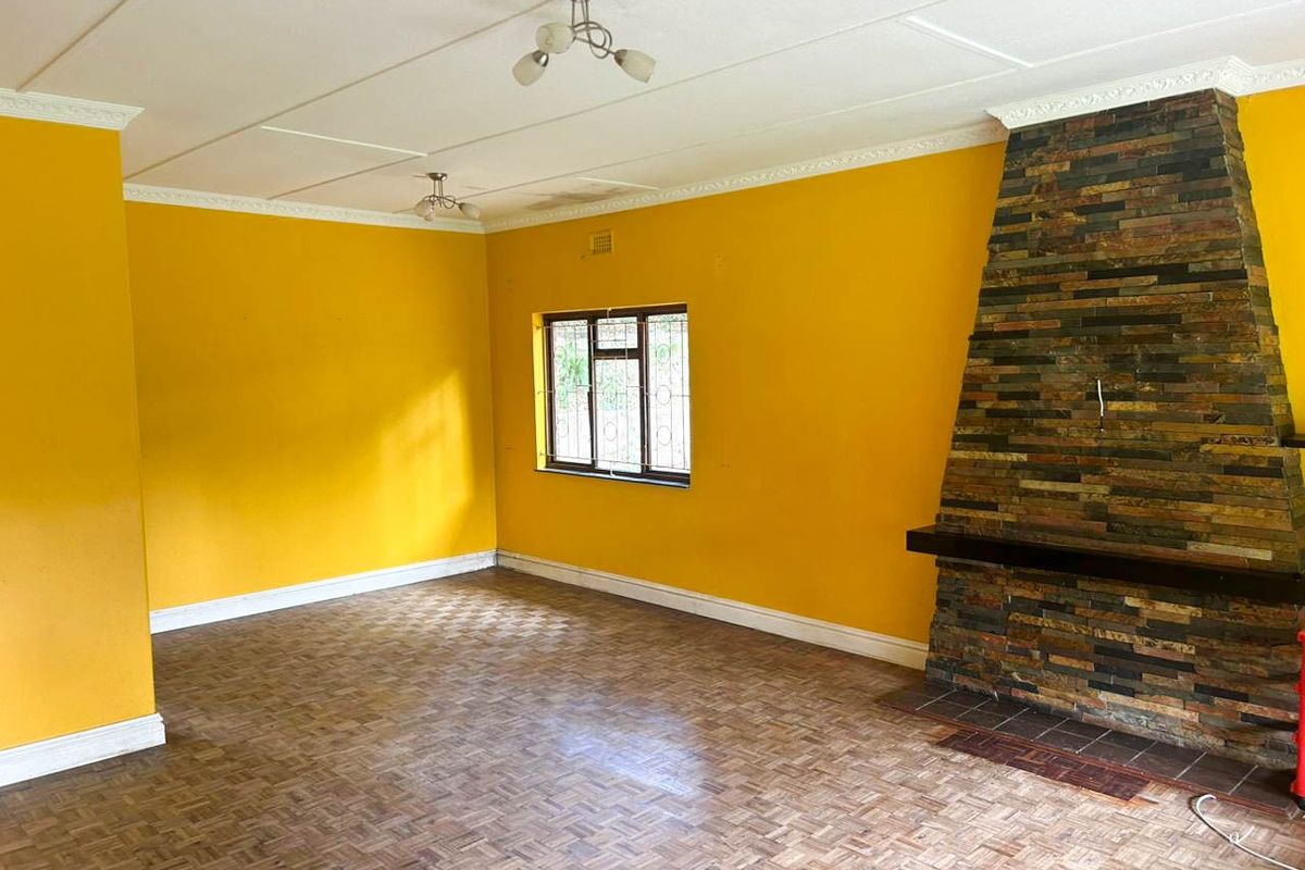 Spacious living room featuring a prominent stone fireplace, parquet flooring, and decorative ceiling cornices, offering a blank canvas for renovation.