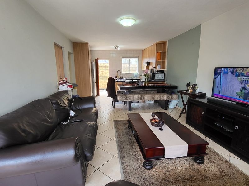 Open-plan living and kitchen area featuring tiled flooring, built-in cabinetry, and a functional breakfast nook, offering a practical layout for daily living.