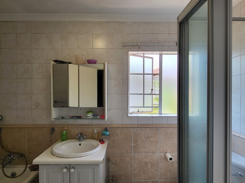 A functional bathroom featuring a vanity cabinet, integrated sink, bathtub, and a separate shower enclosure with tiled wall finishes.
