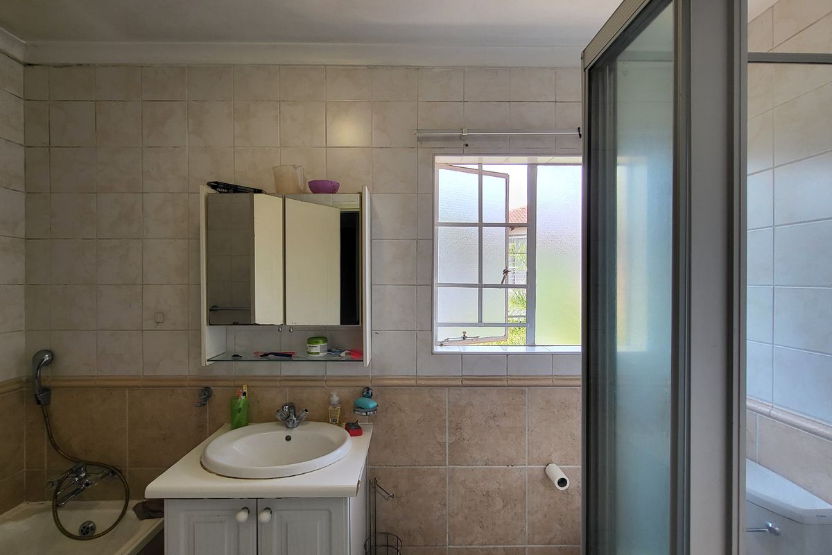 A functional bathroom featuring a vanity cabinet, integrated sink, bathtub, and a separate shower enclosure with tiled wall finishes.