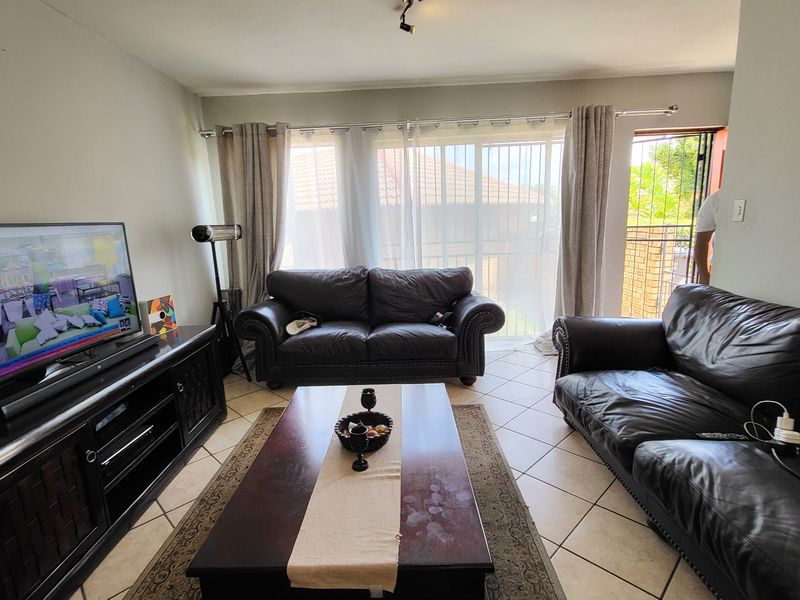 A comfortable living room featuring tiled flooring and a large sliding glass door that provides access to the exterior.