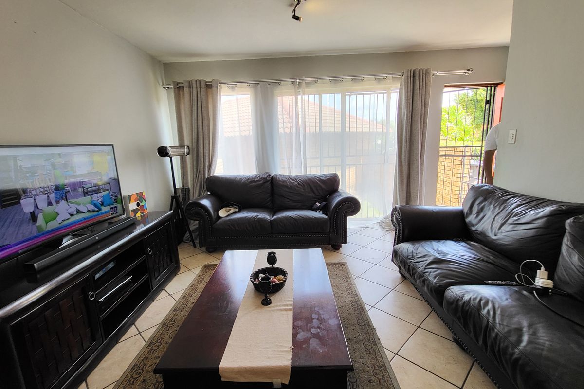 A comfortable living room featuring tiled flooring and a large sliding glass door that provides access to the exterior.