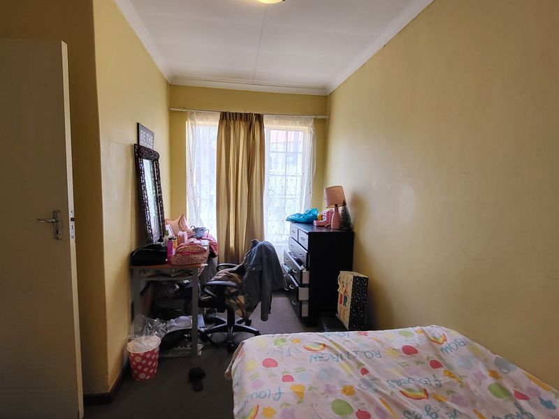 A standard bedroom featuring yellow painted walls and a window with curtain rails, requiring cosmetic updates to improve its overall appeal.