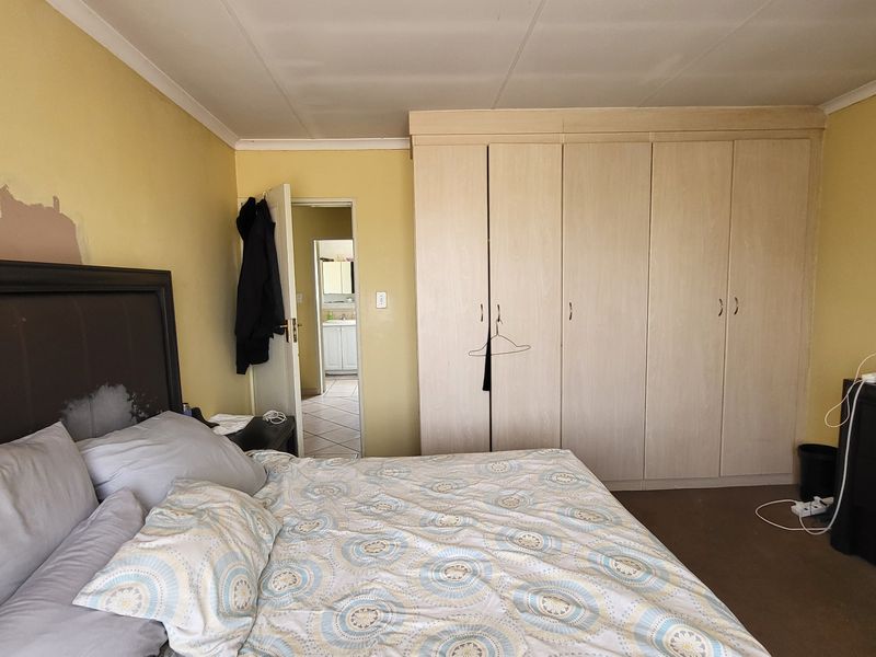 Bedroom featuring built-in cupboards and direct access to an en-suite bathroom. The room requires cosmetic attention to the wall finishes.