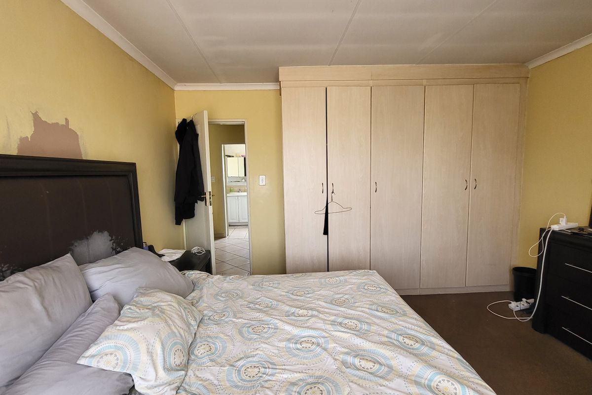 Bedroom featuring built-in cupboards and direct access to an en-suite bathroom. The room requires cosmetic attention to the wall finishes.