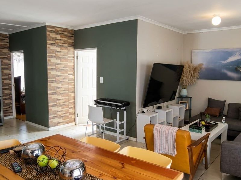 An open-plan living and dining area featuring tiled floors, a decorative stone-cladding feature wall, and neutral wall tones.