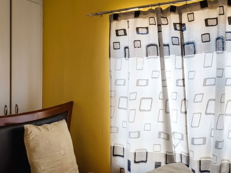 A bedroom featuring yellow walls and a built-in wardrobe with white doors.